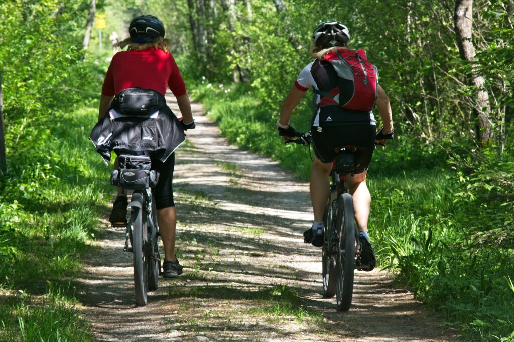 Viaggiatori in bicicletta su un percorso naturale durante una vacanza sostenibile in Italia, tra colline verdi e paesaggi eco-friendly